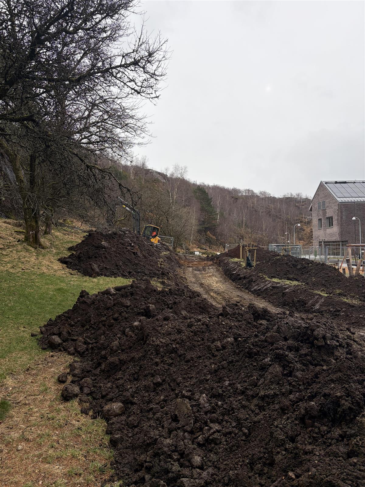 gravemaskin, byggegjerder og en del jord, klarlegger til å bore ettter bergvarme - Klikk for stort bilde